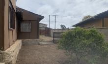  “Vista del patio lateral despejado, donde se observa la primera vivienda de un piso y la segunda vivienda de dos niveles al fondo.